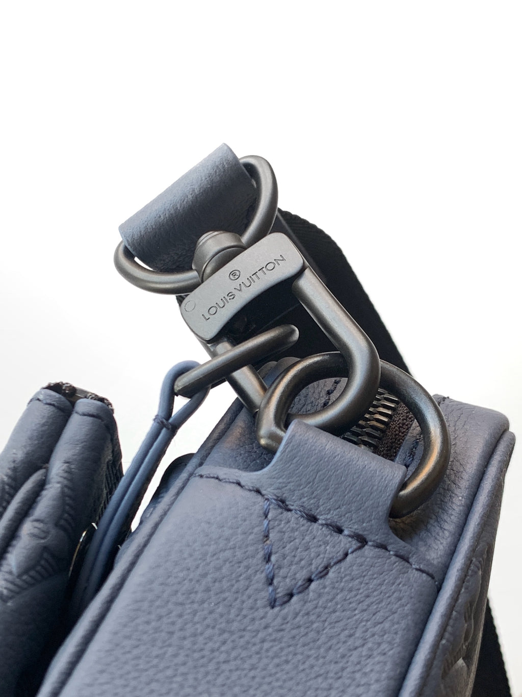 Blue crossbody bag with silver-tone rings and snap hardware at strap connection