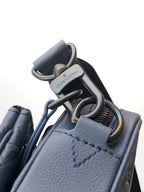 Blue crossbody bag with silver-tone rings and snap hardware at strap connection
