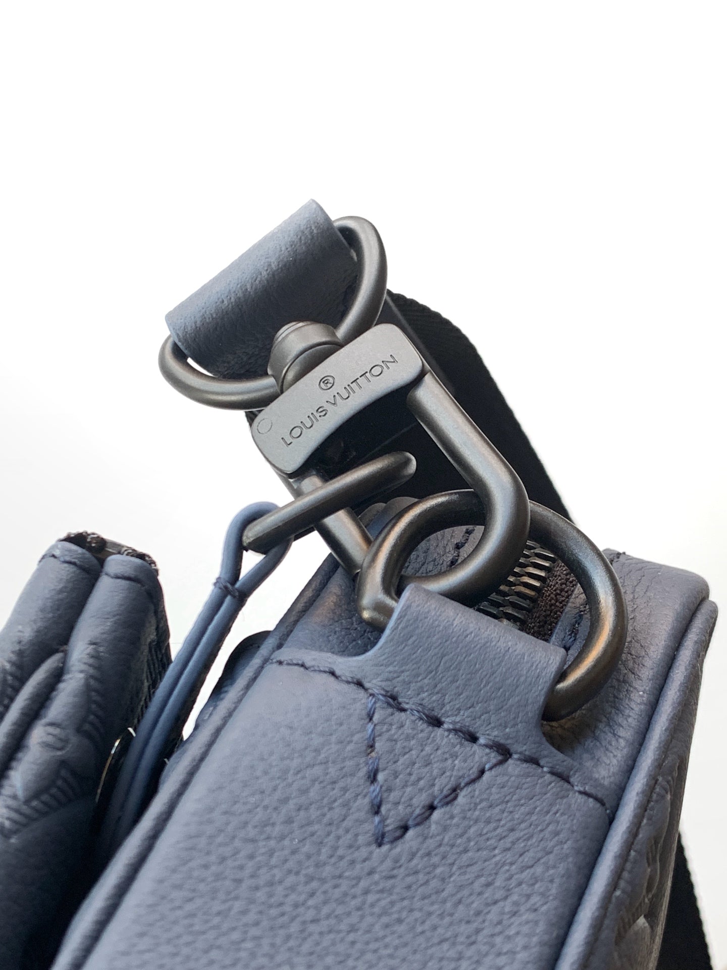 Blue crossbody bag with silver-tone rings and snap hardware at strap connection