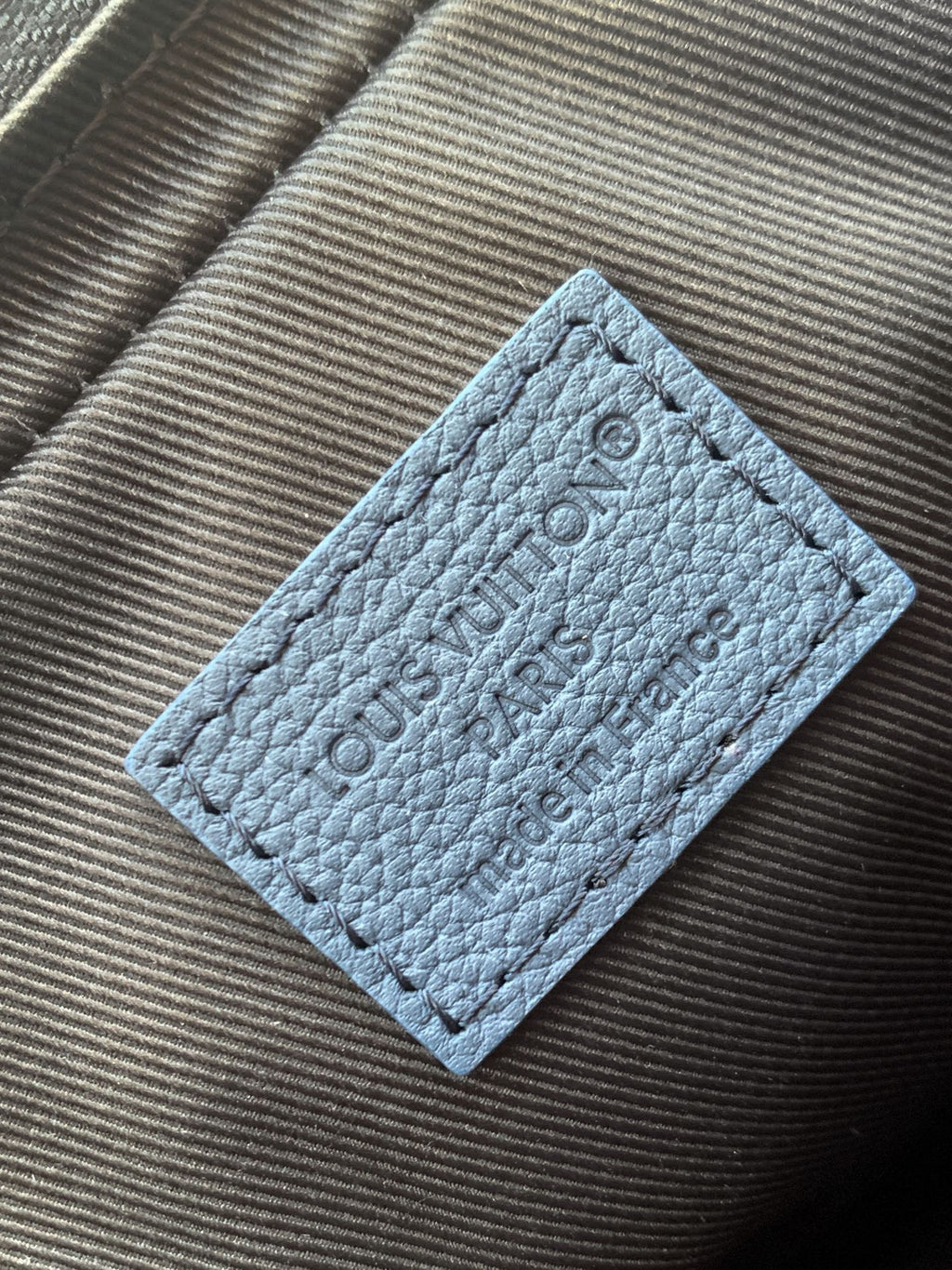 Blue leather interior label with embossed lettering and stitch edges
