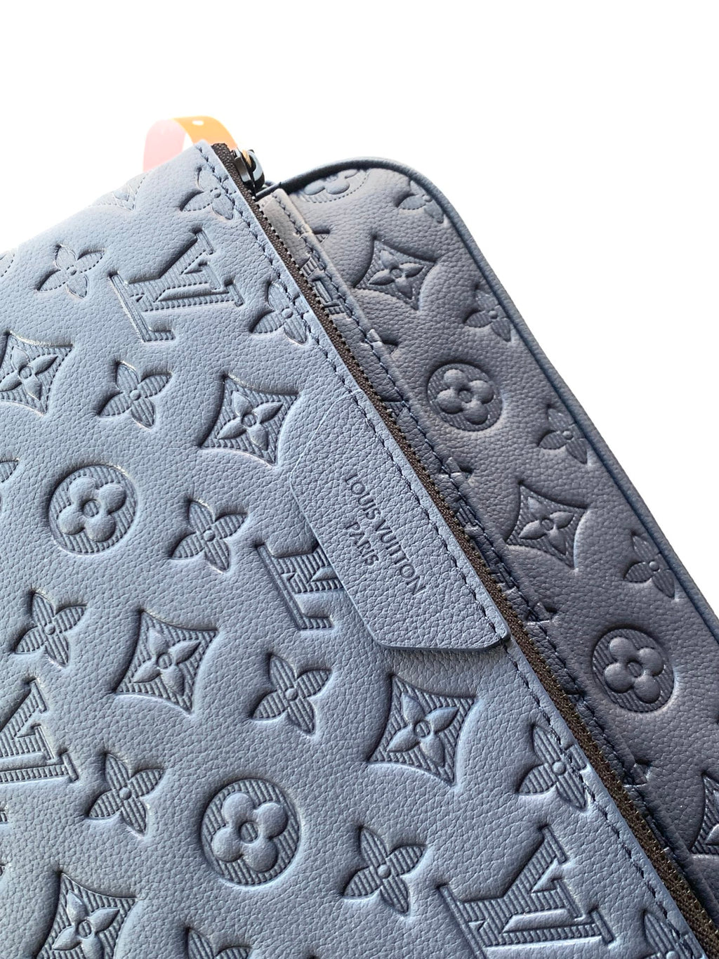 Light blue monogram-embossed crossbody bag panel with zip track and stitching
