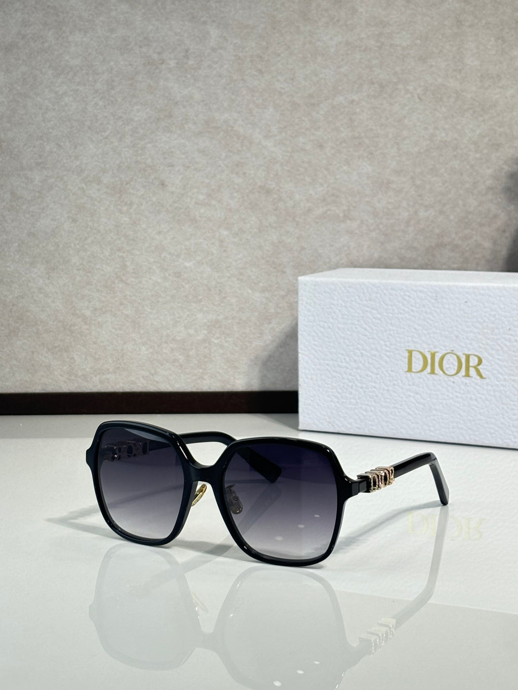 Dior sunglasses with black square frames and dark lenses, gold-tone logo on temple