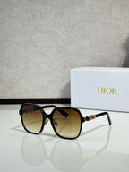 Dior sunglasses with dark frames and amber lenses, gold-tone logo on temple