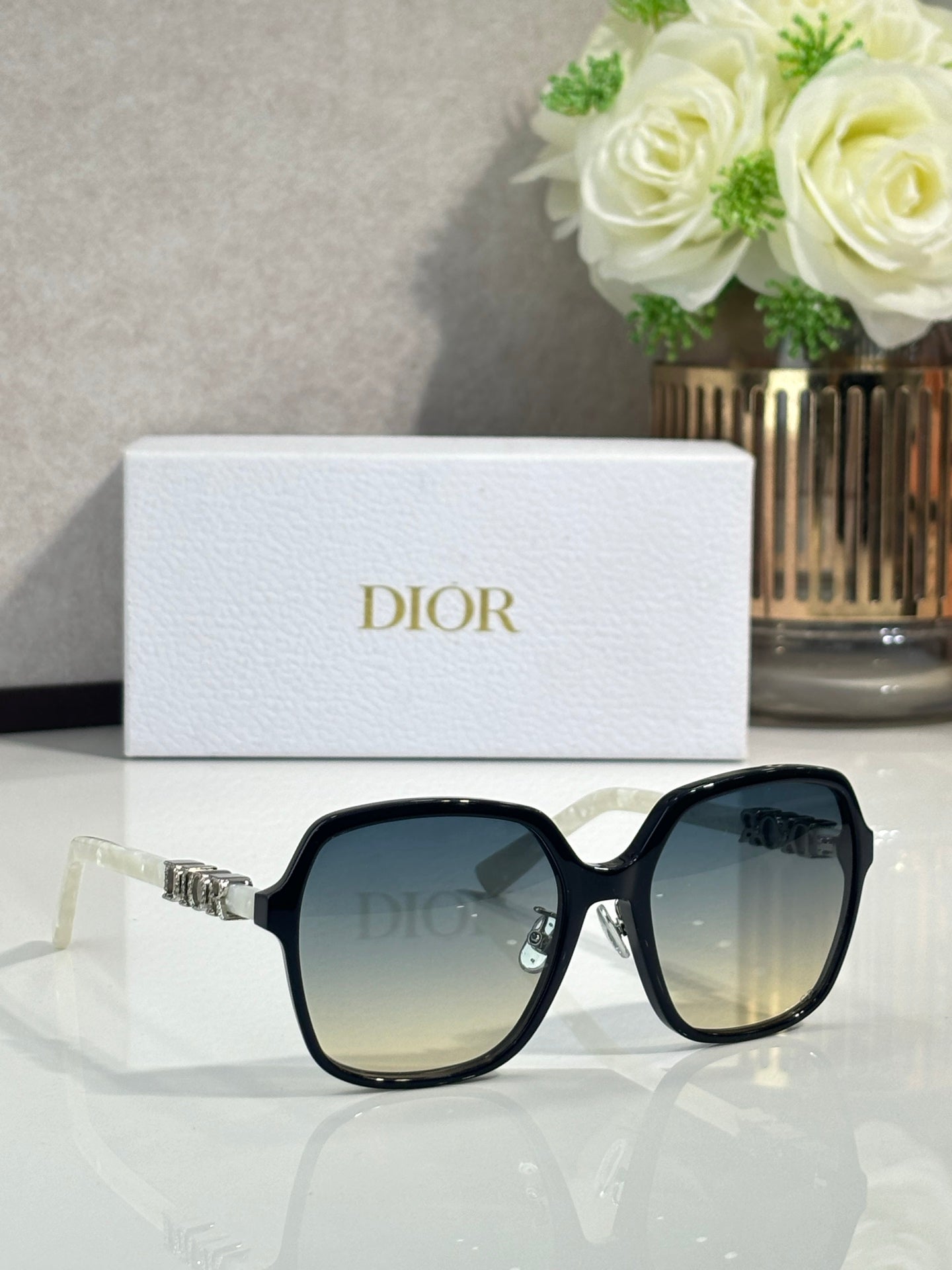 Dior sunglasses with black square frames and warm gradient lenses, silver logo detail