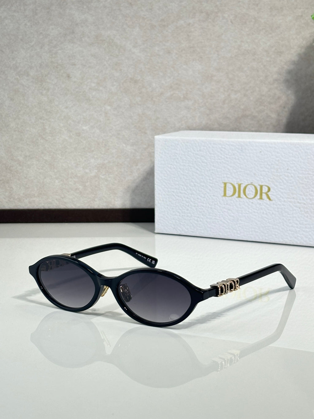 Dior sunglasses with black frame and oval dark lenses, gold bridge detail.