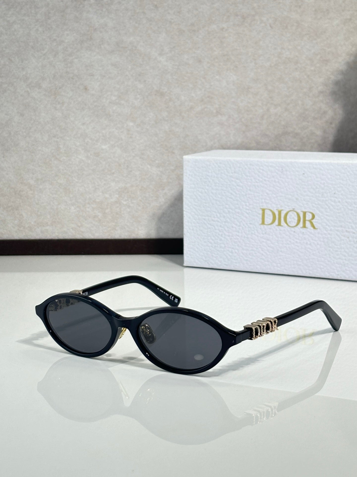 Dior sunglasses with black frame and oval dark lenses, gold bridge detail.