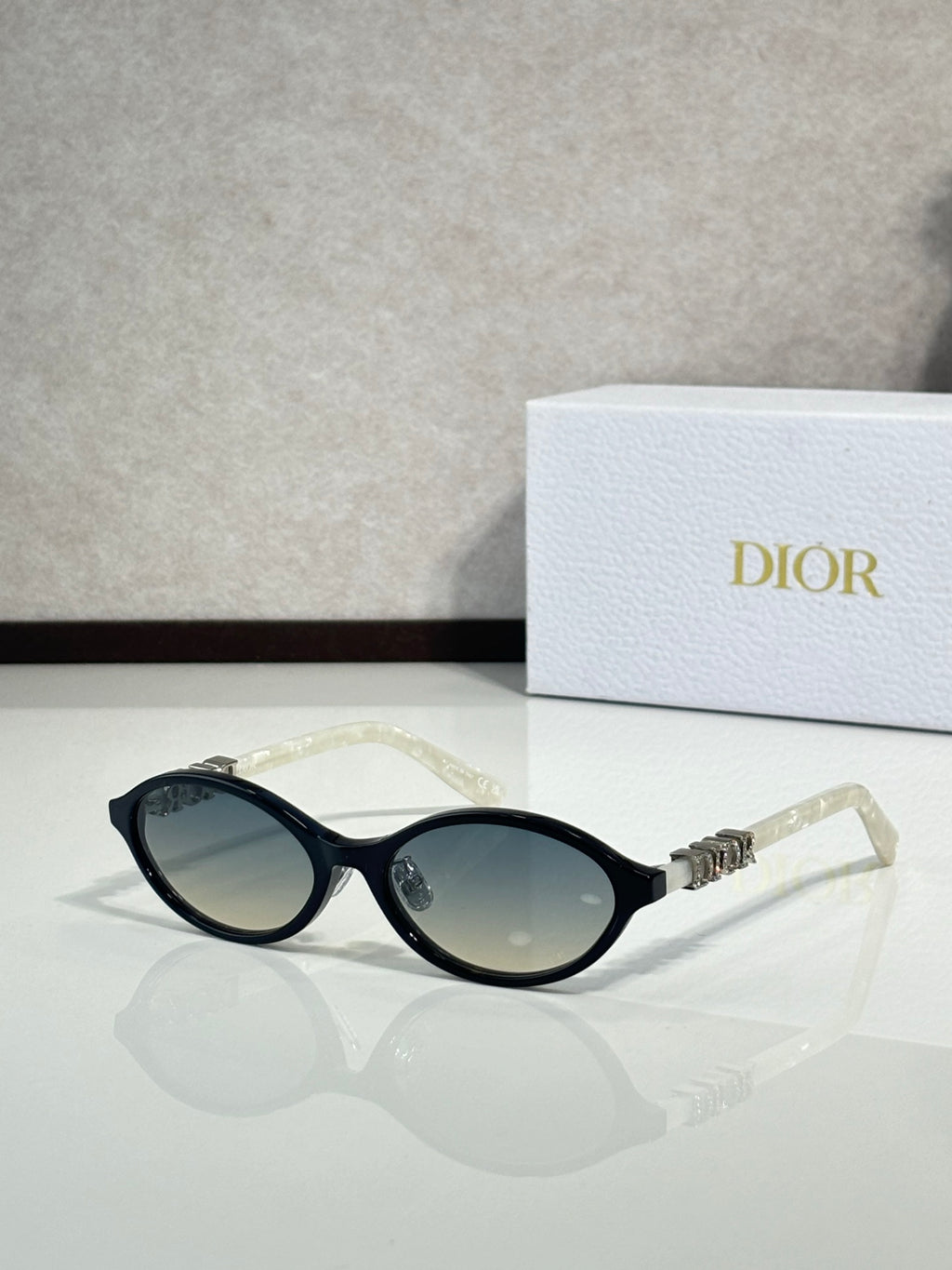 Dior sunglasses with black frame and oval dark lenses, clear temple tips.
