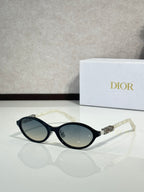 Dior sunglasses with black frame and oval dark lenses, clear temple tips.