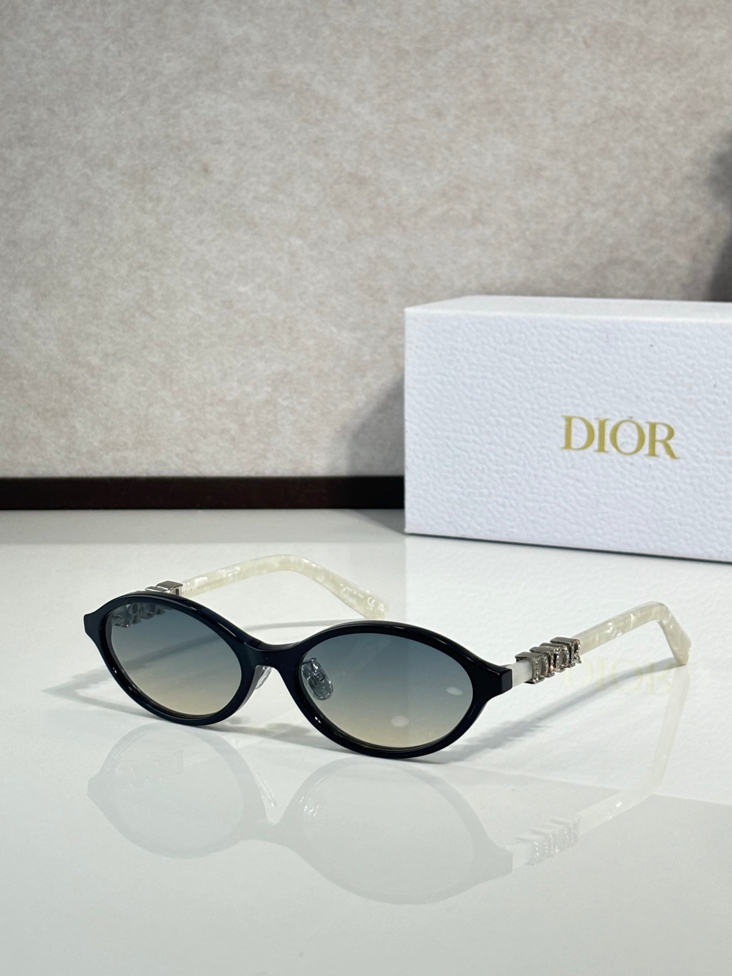 Dior sunglasses with black frame and oval dark lenses, clear temple tips.