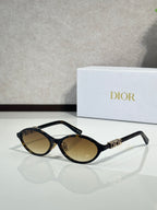 Dior sunglasses with black frame and oval amber lenses, gold bridge detail.