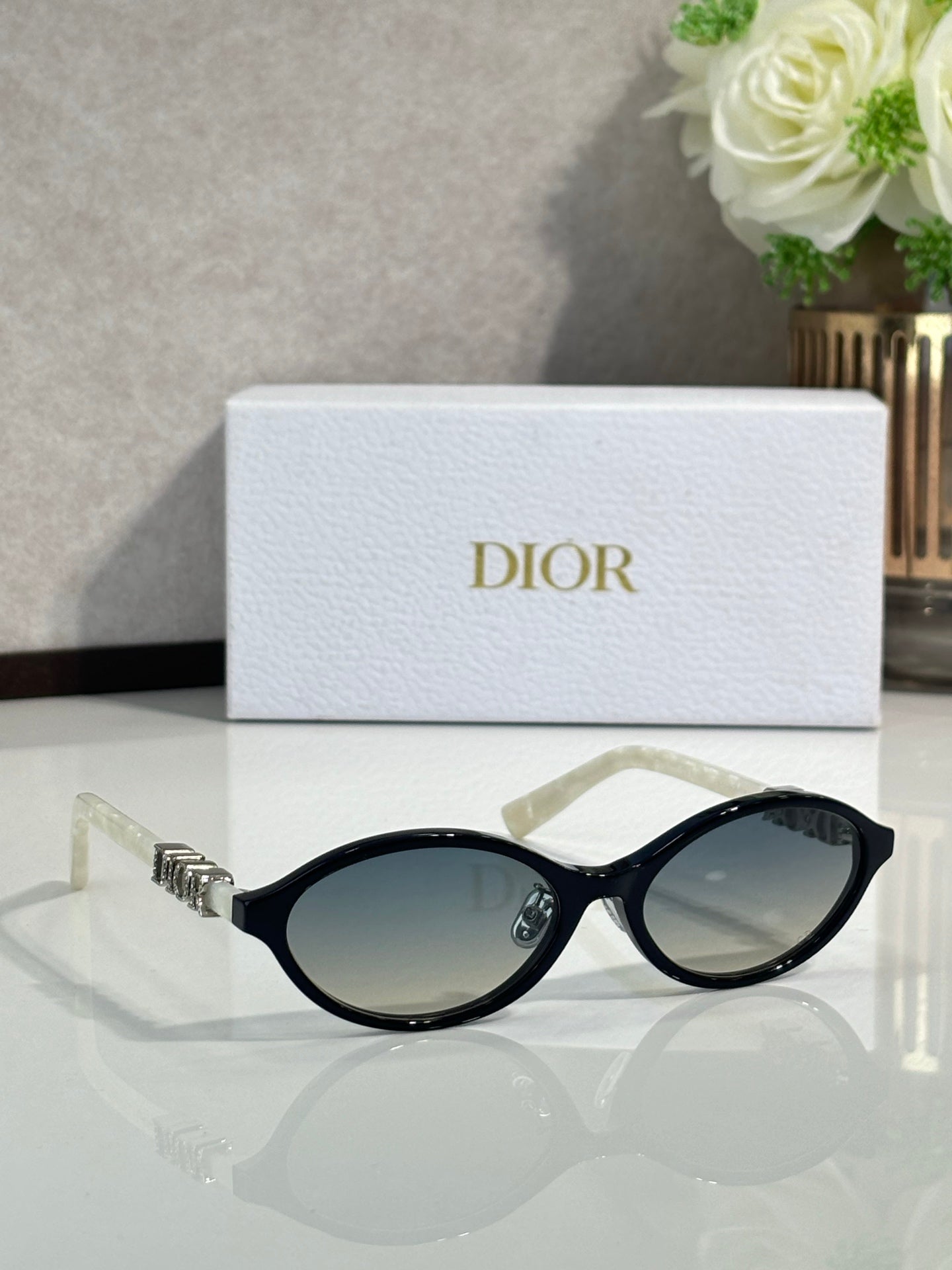 Dior sunglasses with black frame and oval dark lenses, front view.