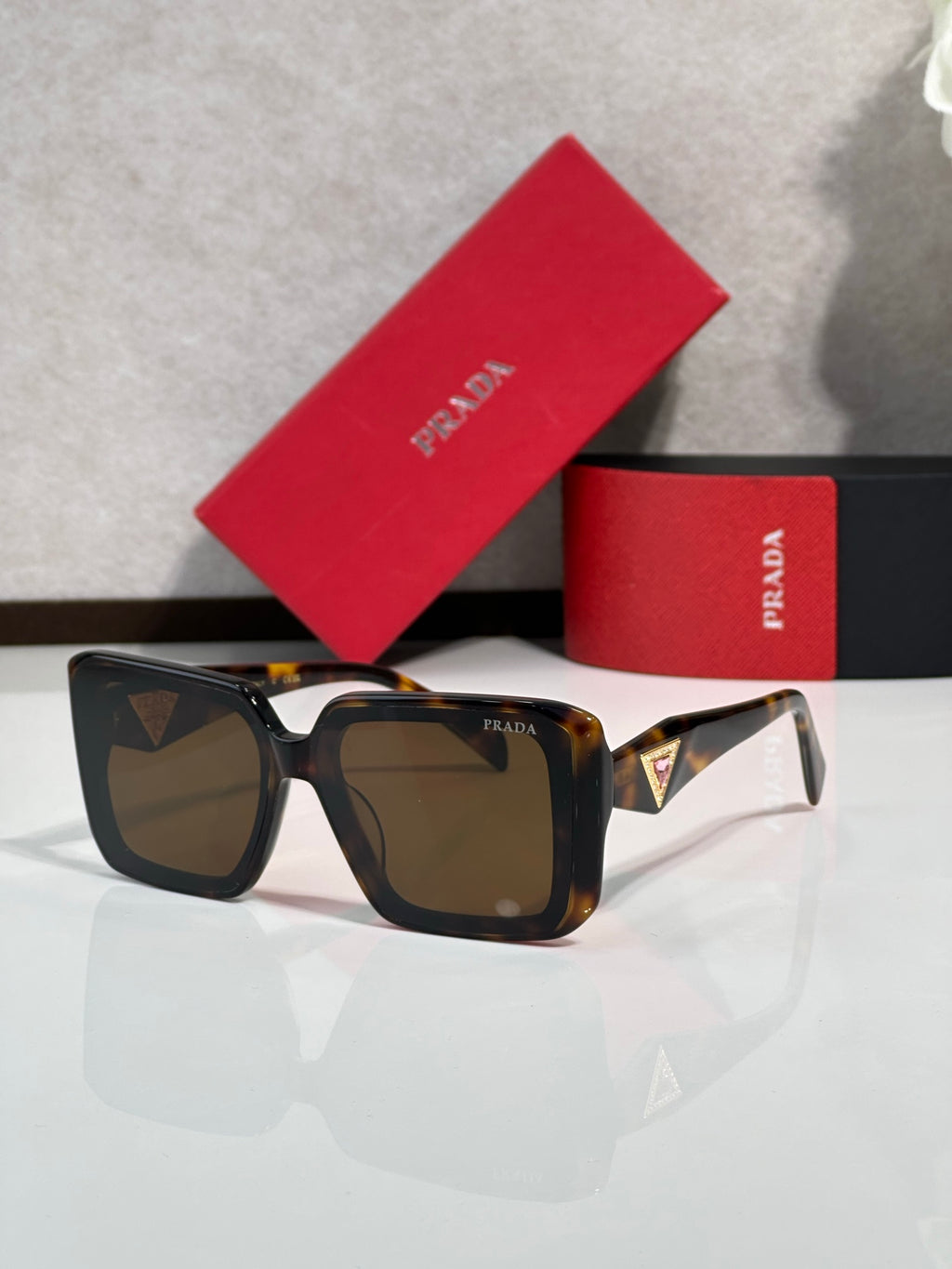Black oversized square sunglasses with brown-tinted lenses, Prada temple logo