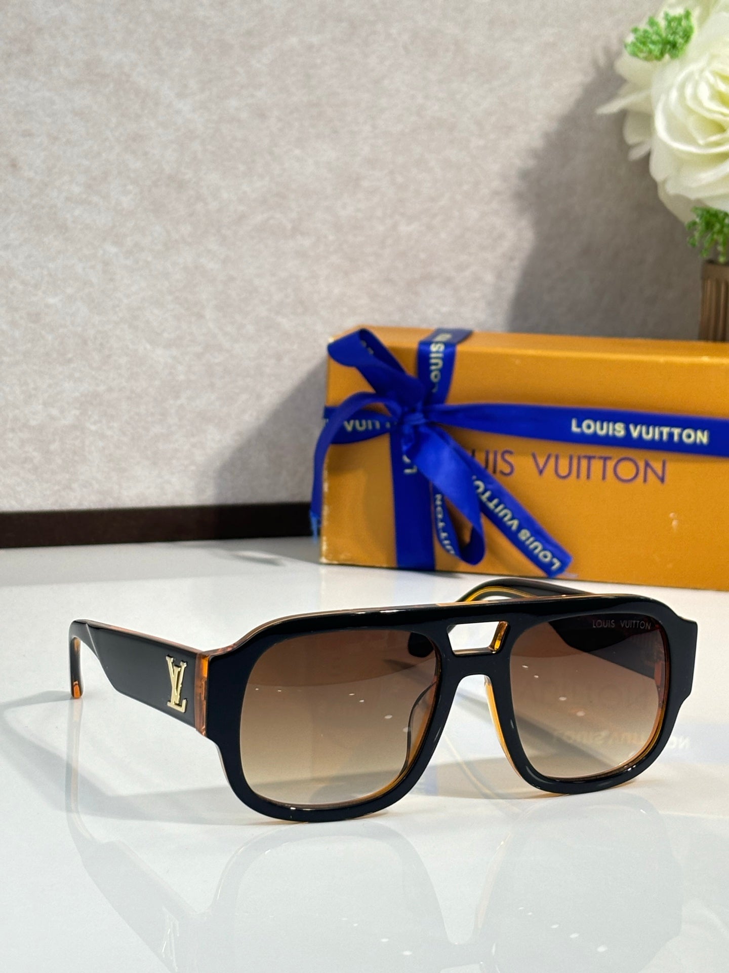 Black fashion sunglasses with brown gradient lenses and gold logo on temples