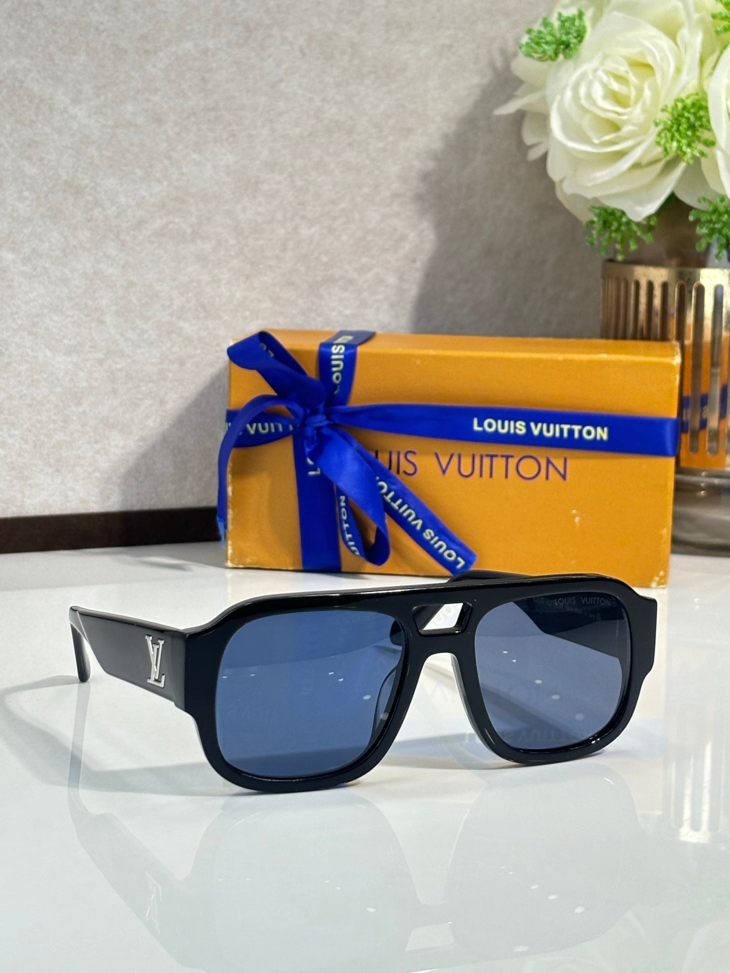 Black oversized fashion sunglasses with dark blue lenses and gold logo detailing