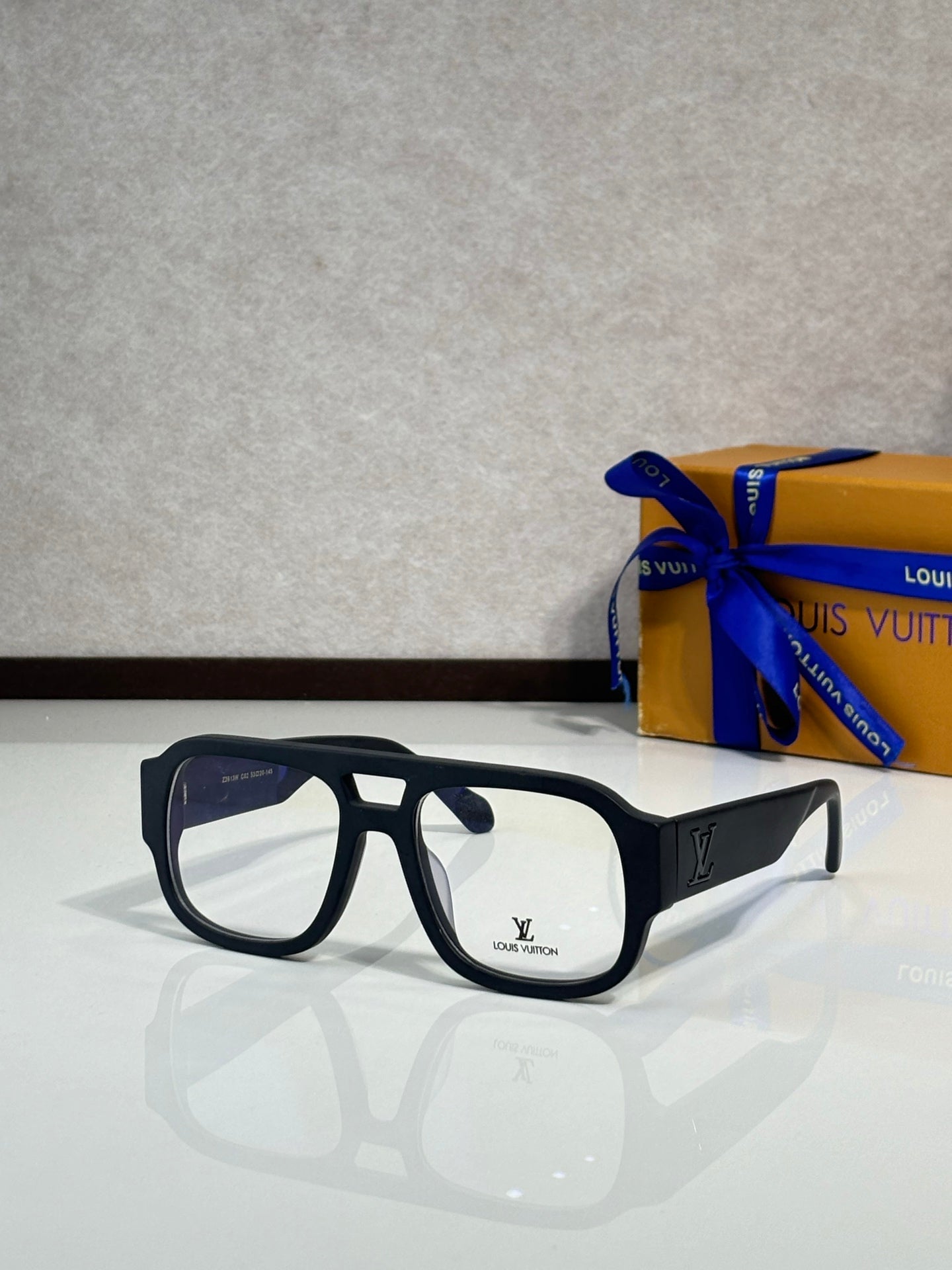 Black fashion sunglasses with clear lenses and gold logo on temples, angled