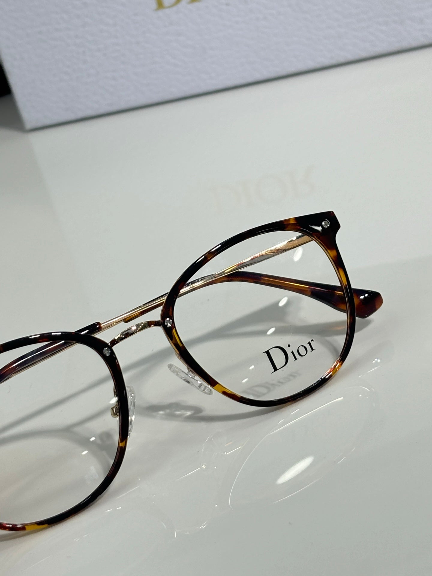 Dior eyeglasses close-up with tortoise round frames and clear lens, logo detail