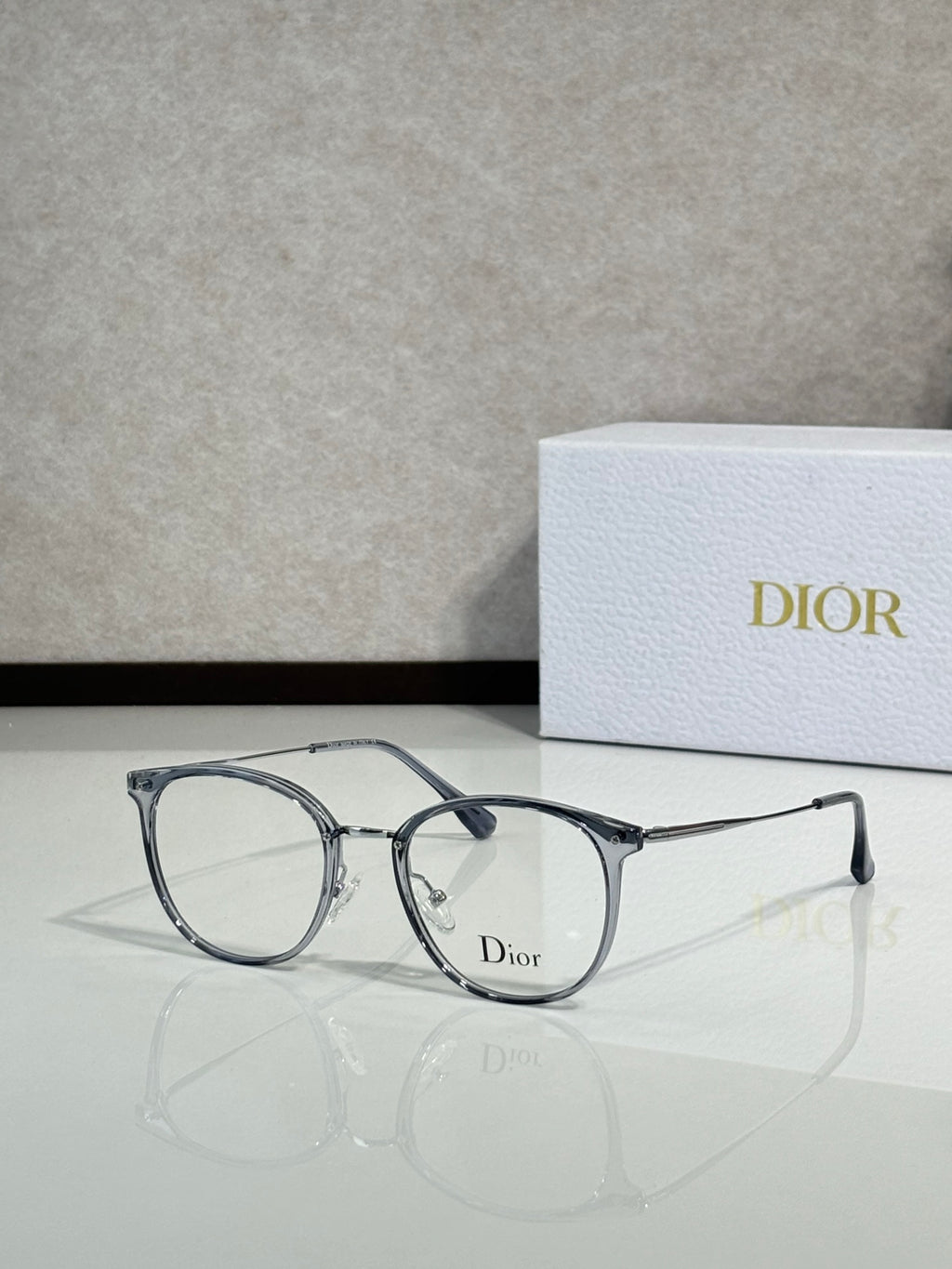 Dior eyeglasses with light blue-gray round frames and clear lenses, logo on bridge