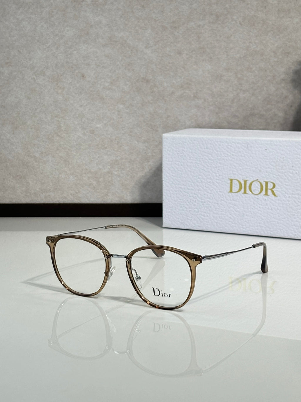 Dior eyeglasses with gold brown round frames and clear lenses, logo on lens