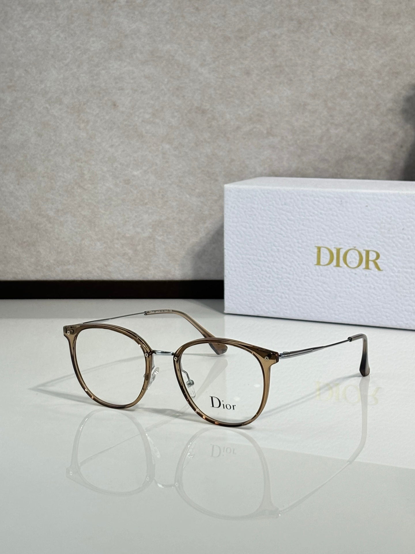 Dior eyeglasses with gold brown round frames and clear lenses, logo on lens