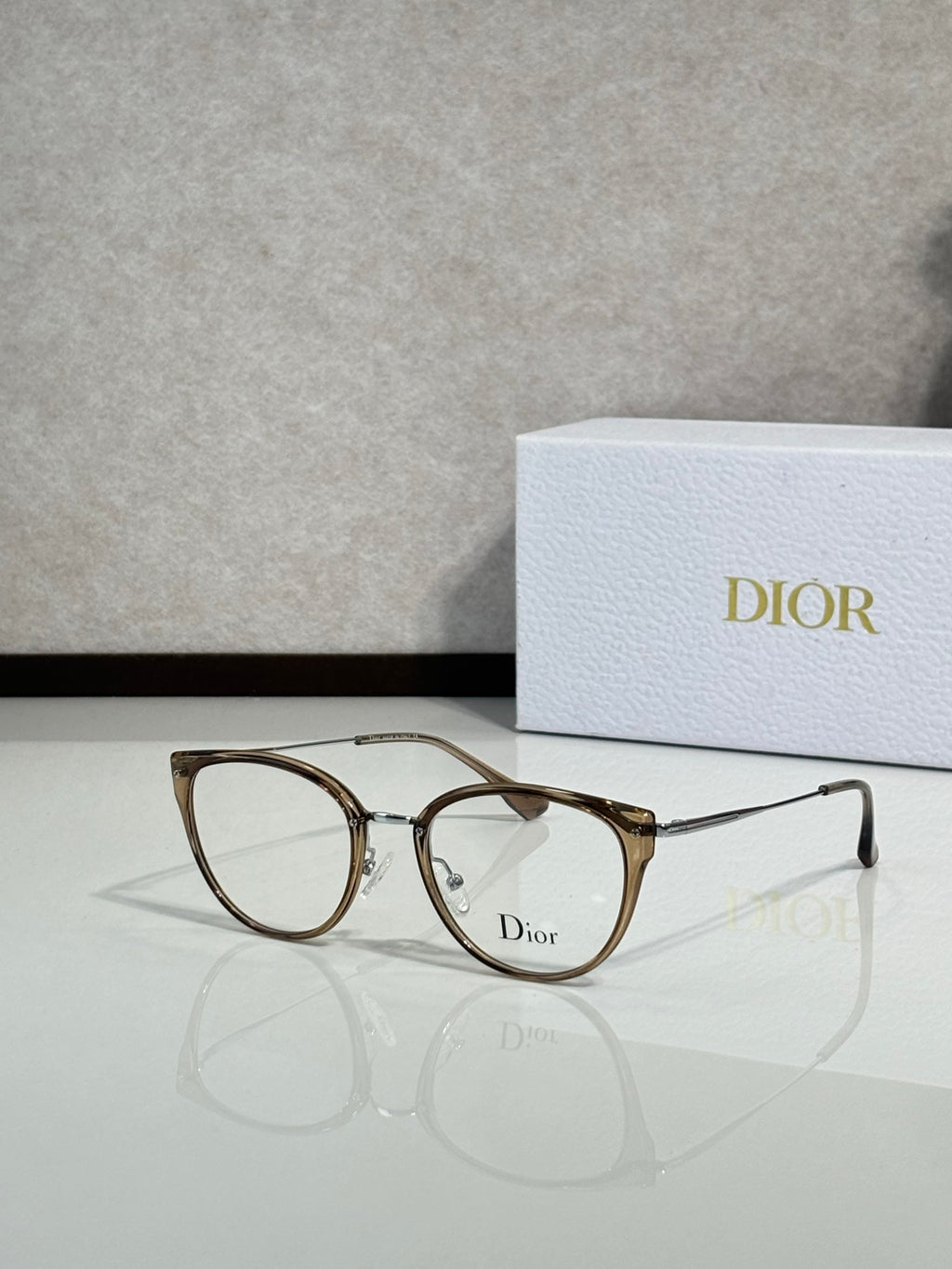Gold-brown round eyeglasses with thin metal temples and Dior logo on lens