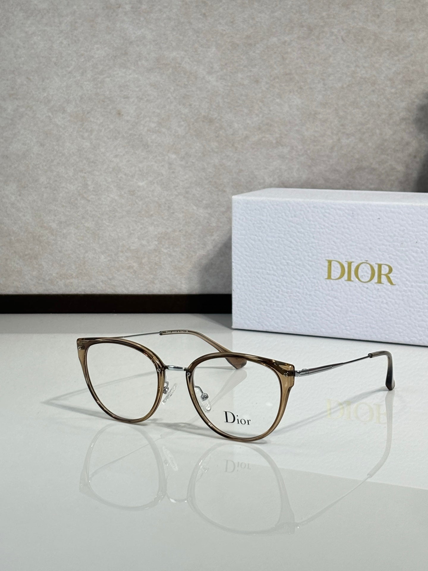 Gold-brown round eyeglasses with thin metal temples and Dior logo on lens