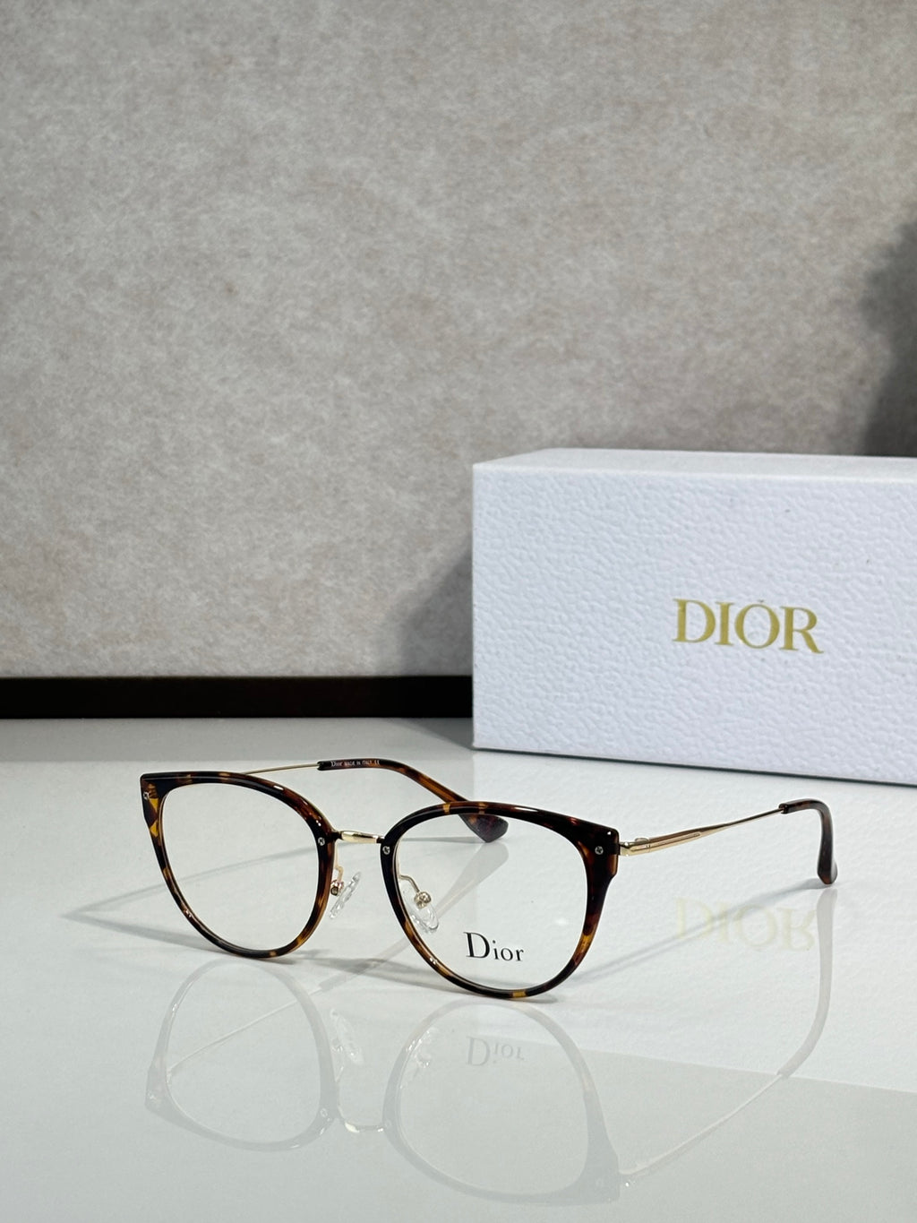 Brown tortoiseshell round eyeglasses with gold-tone temples and Dior logo on lens