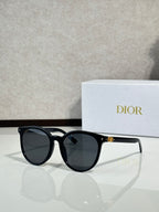 Sunglasses with glossy black frame and dark lenses, rounded cat-eye shape
