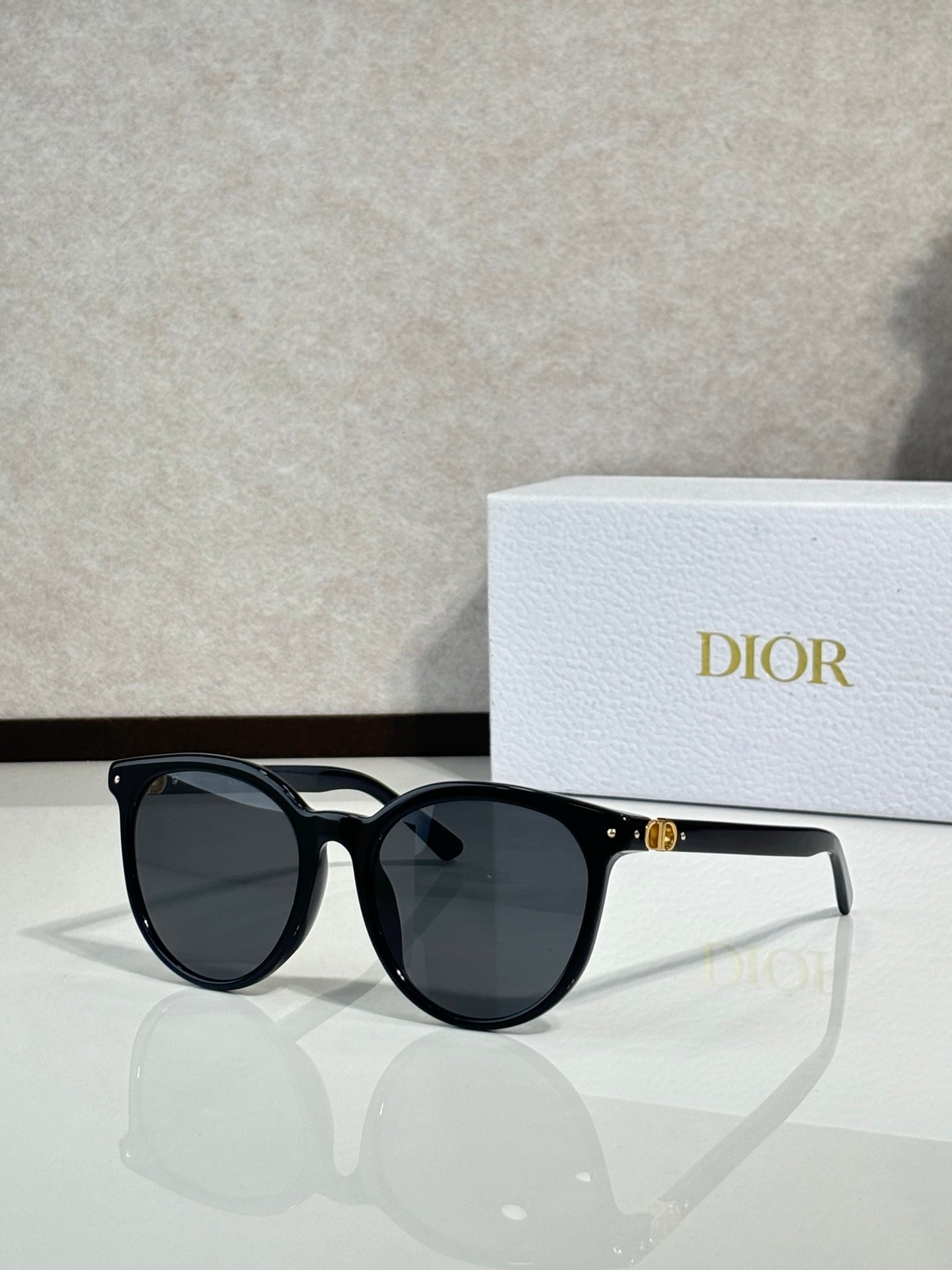 Sunglasses with glossy black frame and dark lenses, rounded cat-eye shape