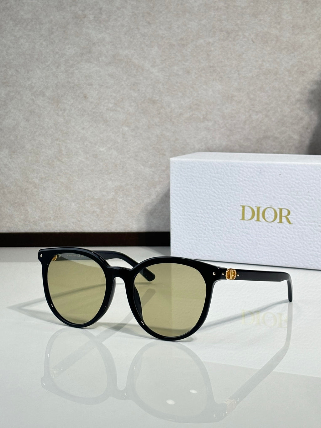 Sunglasses with black frame and olive-tinted lenses, rounded cat-eye shape