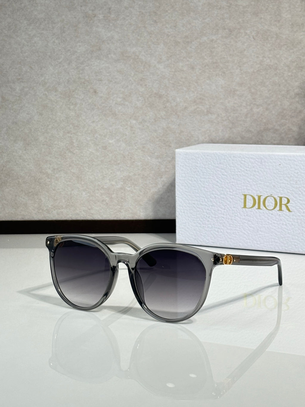 Sunglasses with translucent silver frame and dark lenses, rounded cat-eye shape