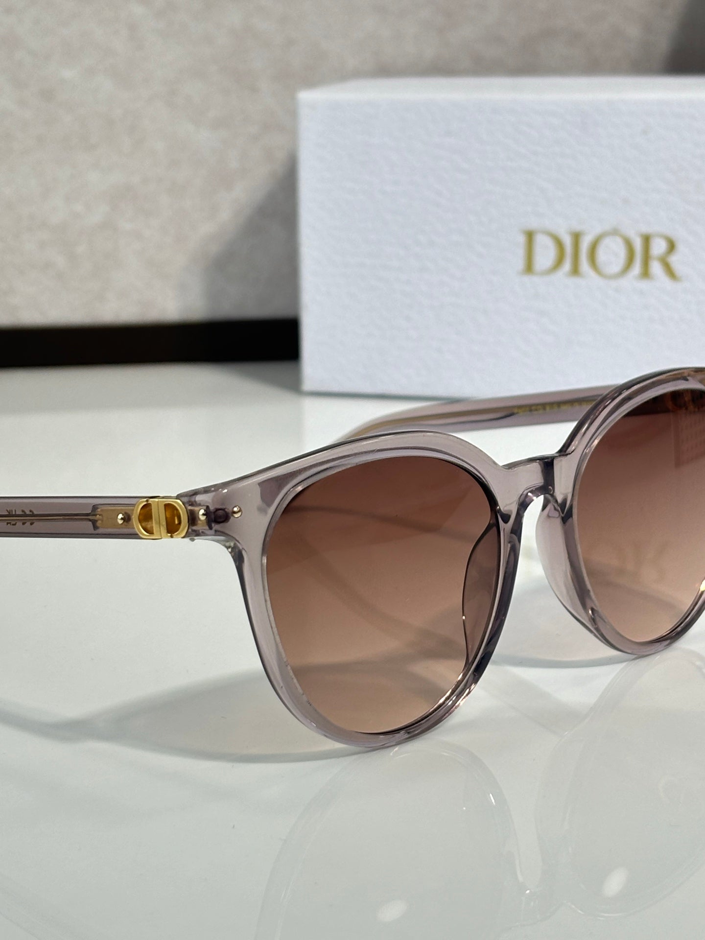 Sunglasses close-up with translucent silver frame and brown gradient lenses, cat-eye shape