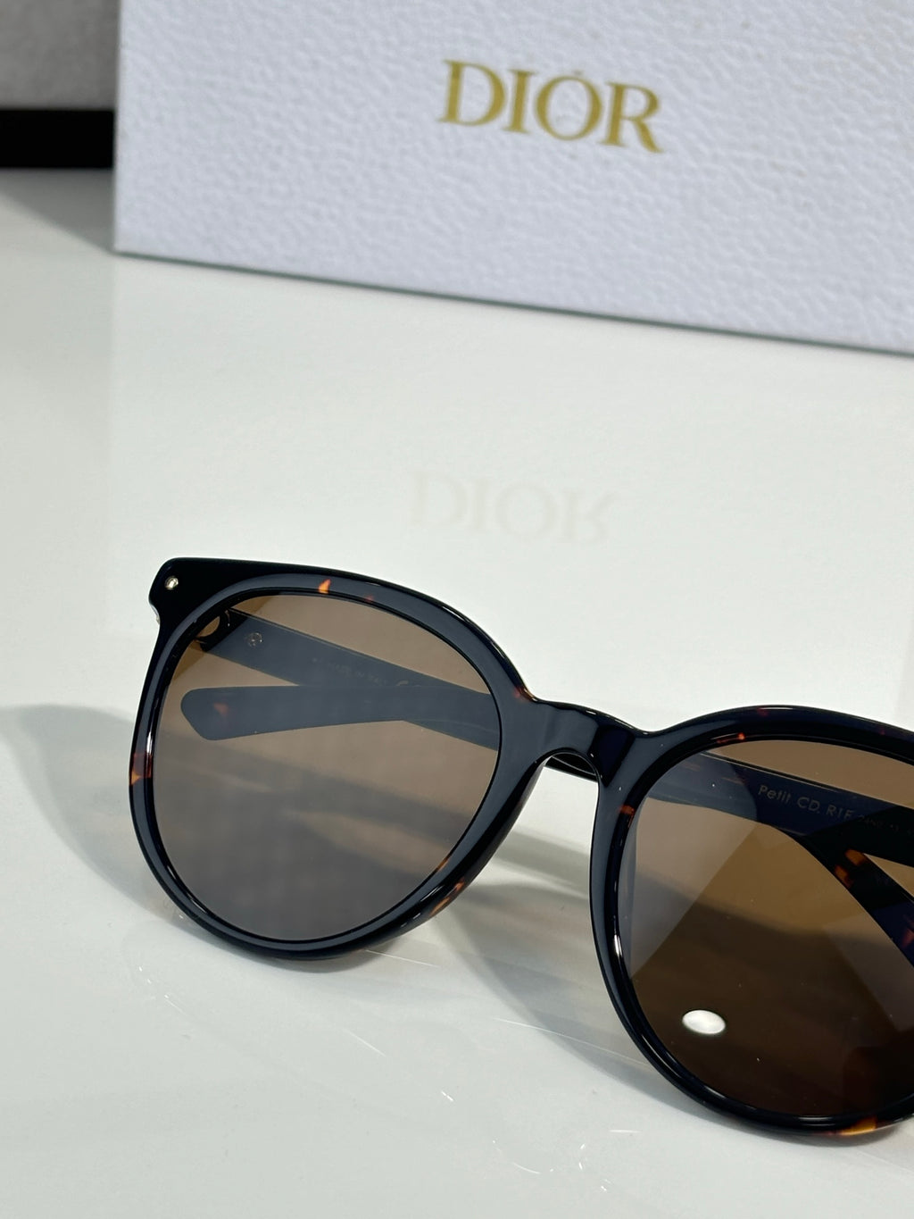 Sunglasses close-up with dark frame and brown tinted lenses, rounded cat-eye shape