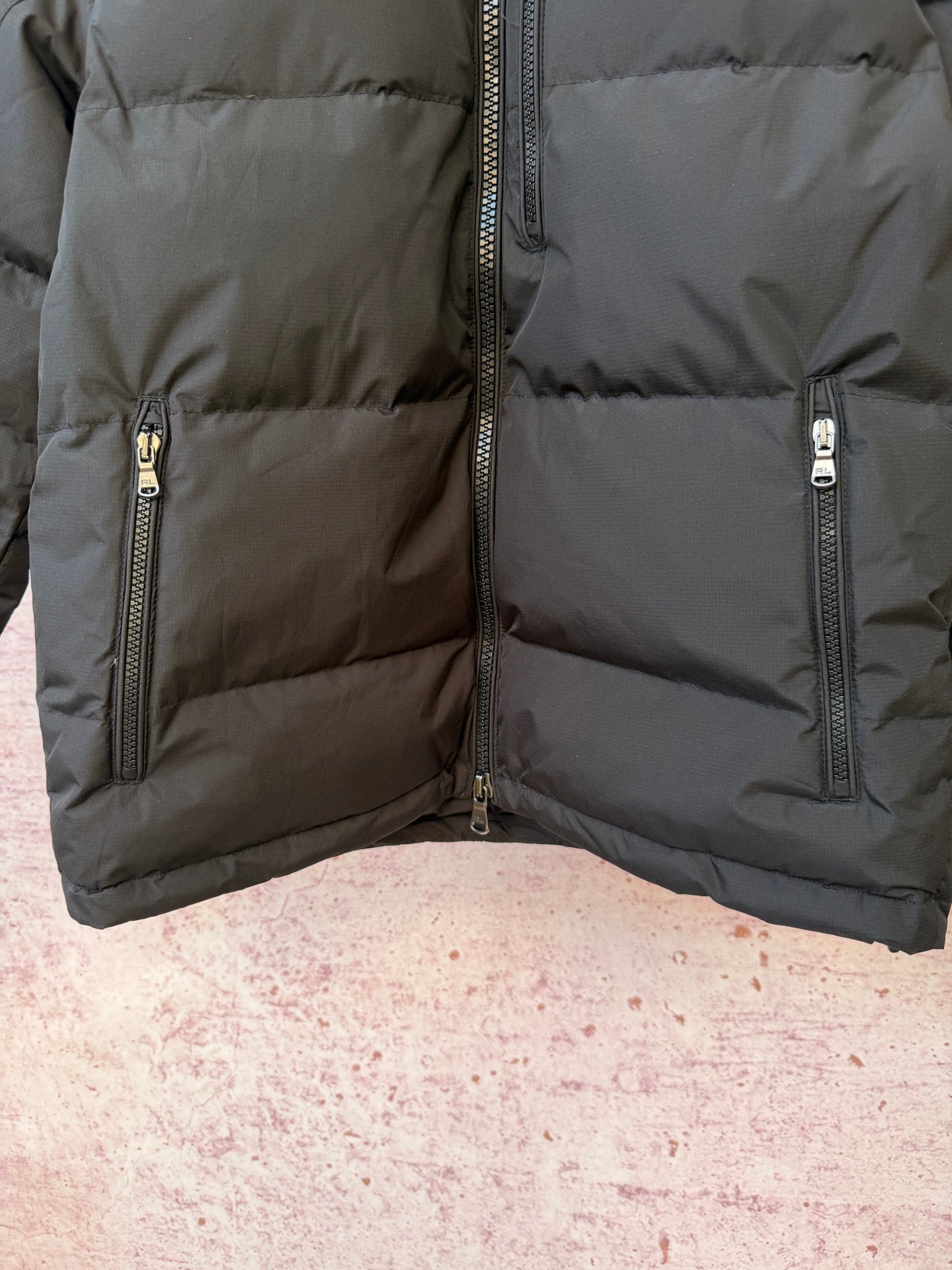 Dark puffer jacket lower panel with quilted baffles and front zipper