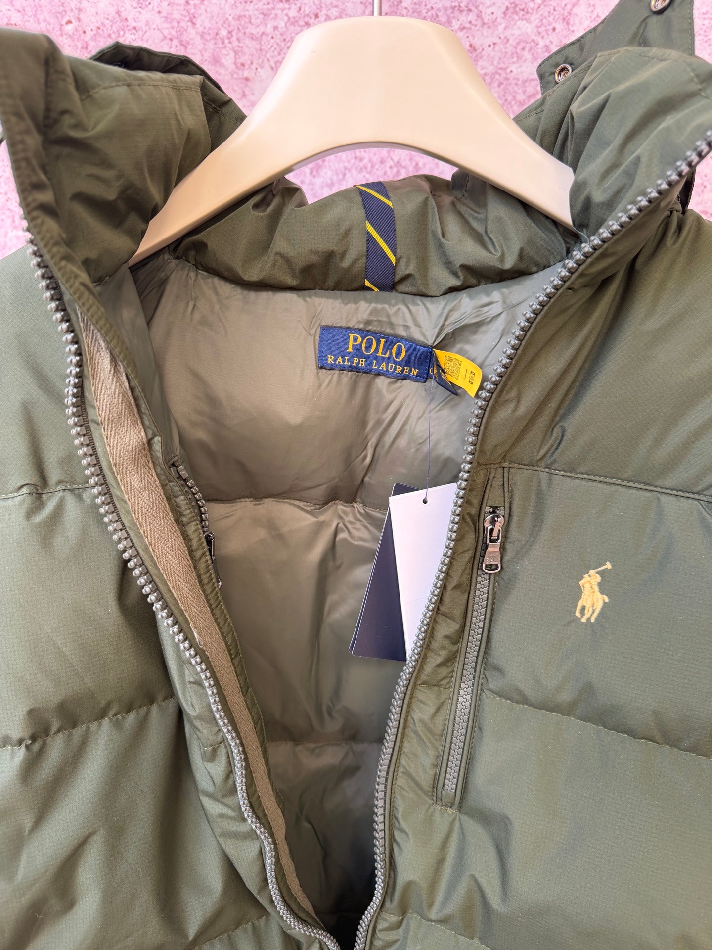 Olive puffer jacket interior with hood lining, front zipper, and small logo