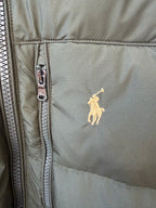 Olive puffer jacket close-up with silver zipper and small yellow polo logo