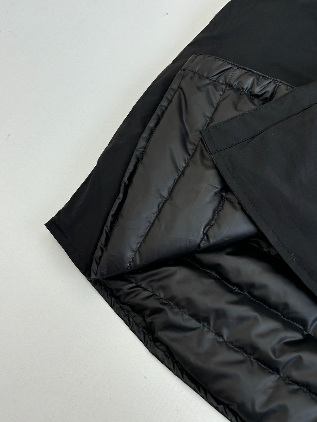 Black quilted interior lining of a long jacket, partially folded open