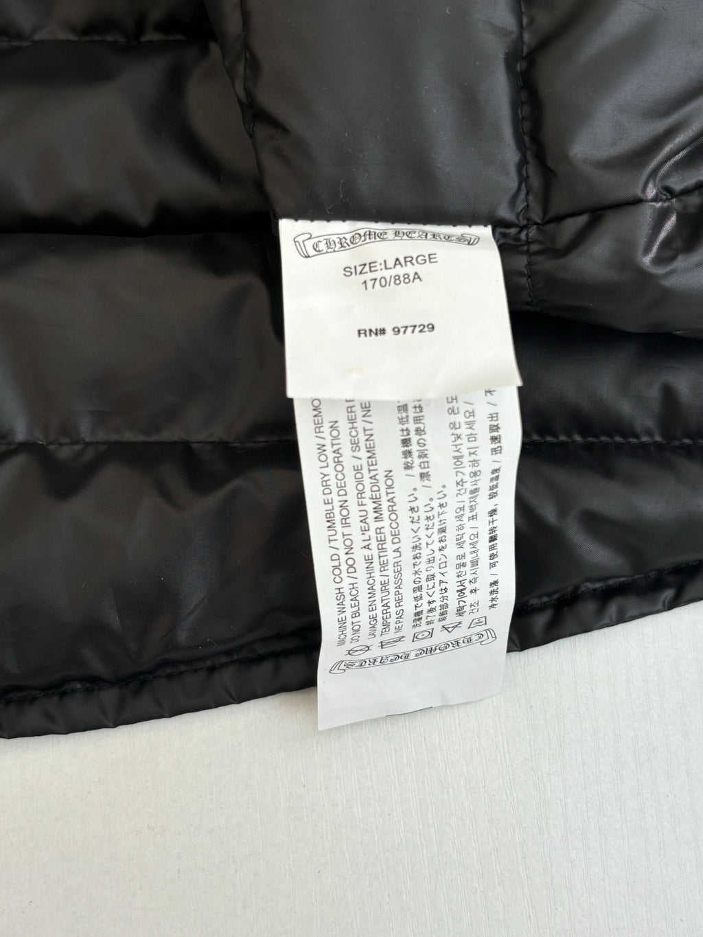 Long padded jacket with size and care labels on dark fabric