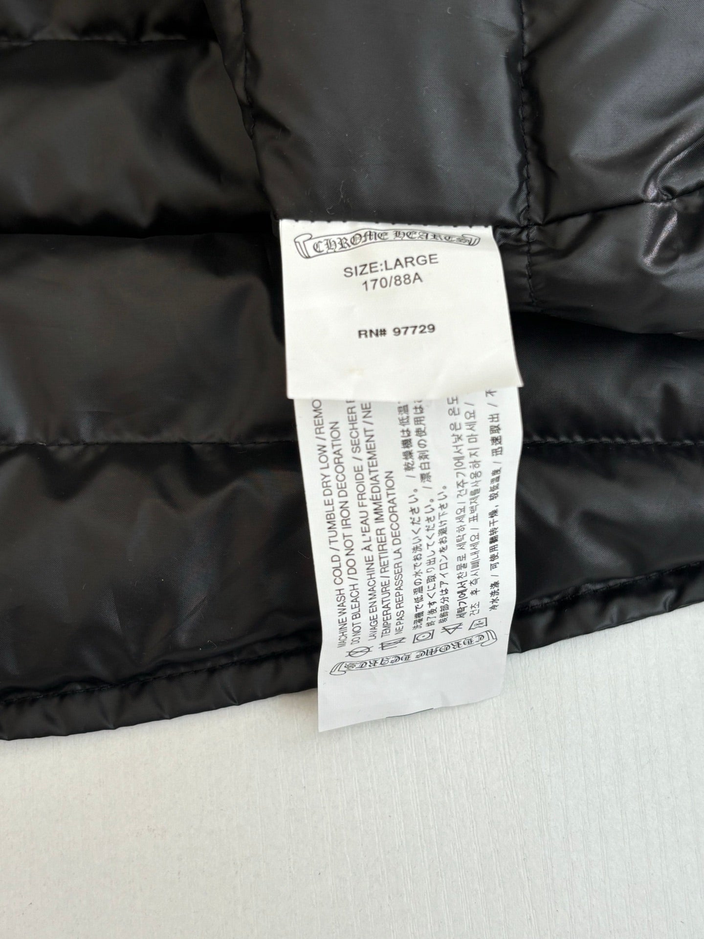 Long padded jacket with size and care labels on dark fabric