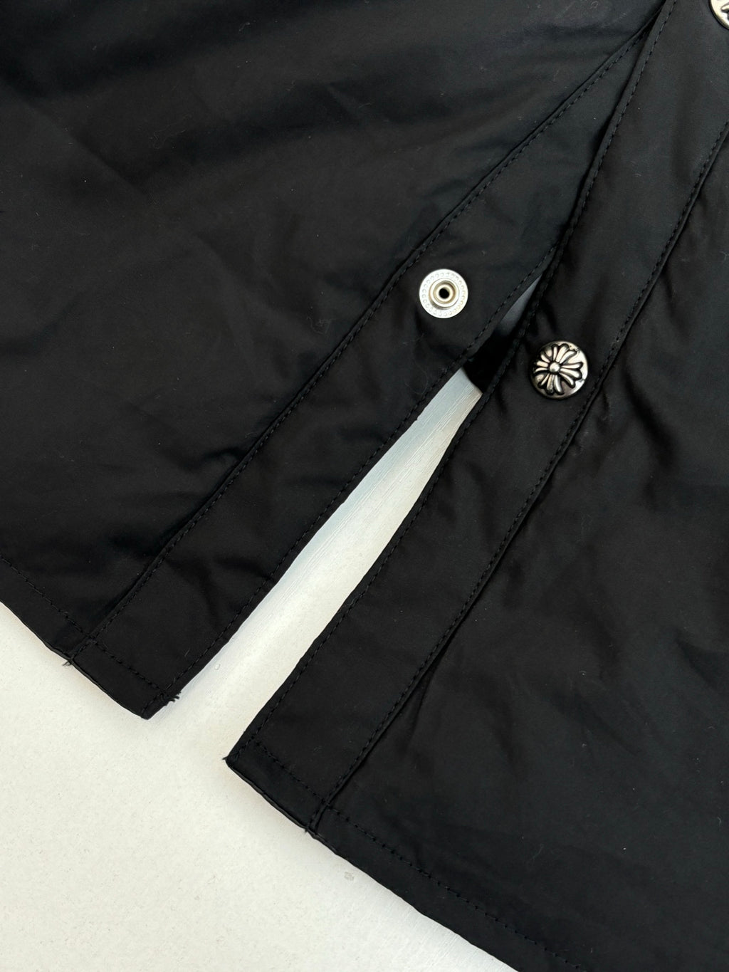 Close-up of black jacket sleeve and shoulder seam with round snap button details
