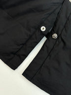 Close-up of black jacket sleeve and shoulder seam with round snap button details