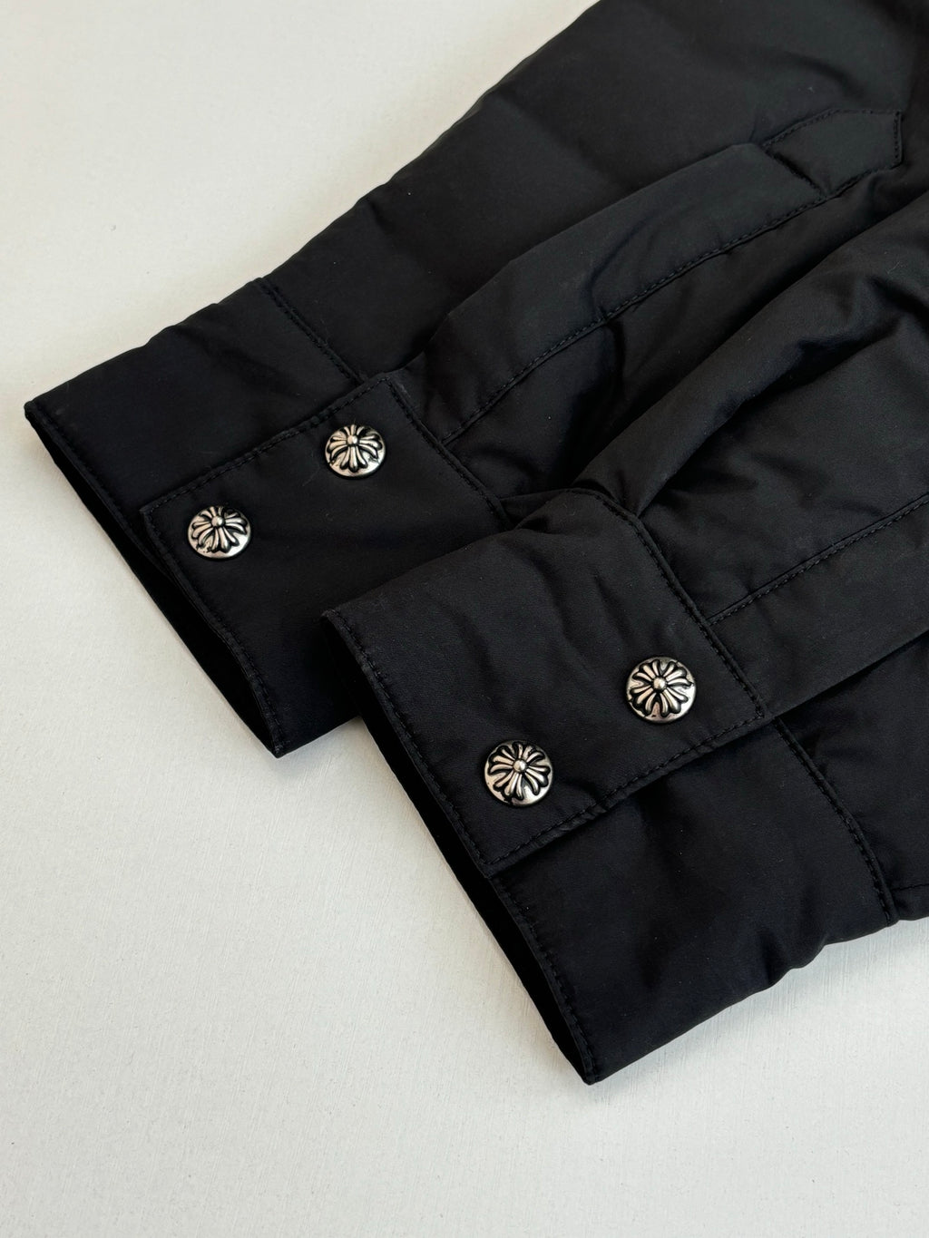 Black jacket sleeve cuffs and decorative button closures, laid flat