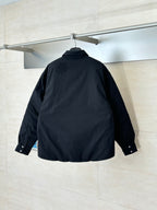 Back view of black long-sleeve button-up jacket with stand collar, hanging on a rail