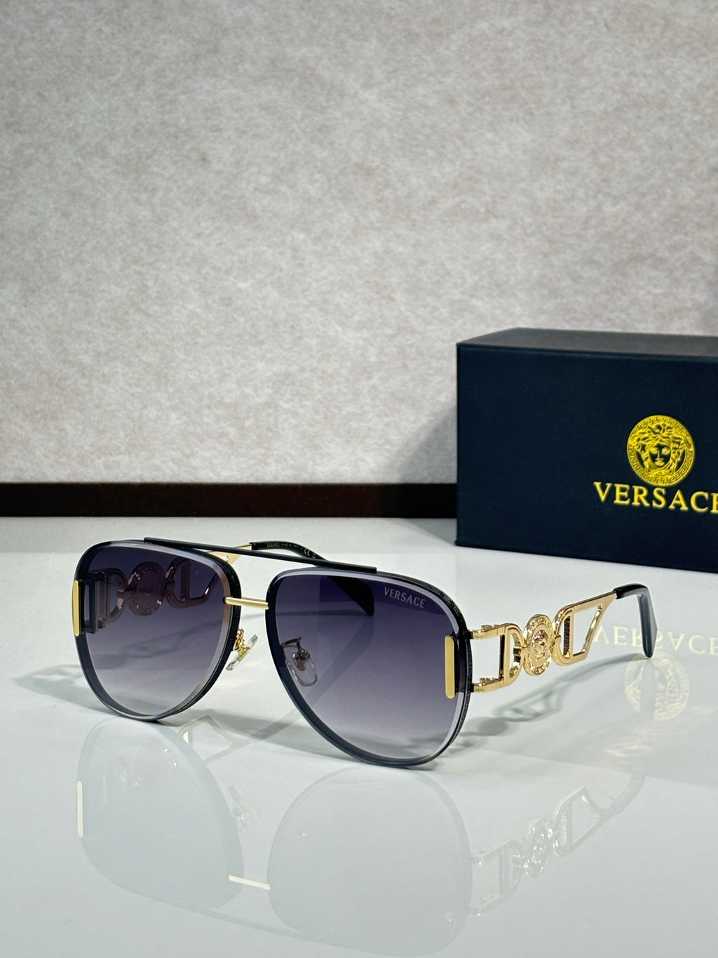 Versace sunglasses with black frame, gold details, and dark gradient lenses