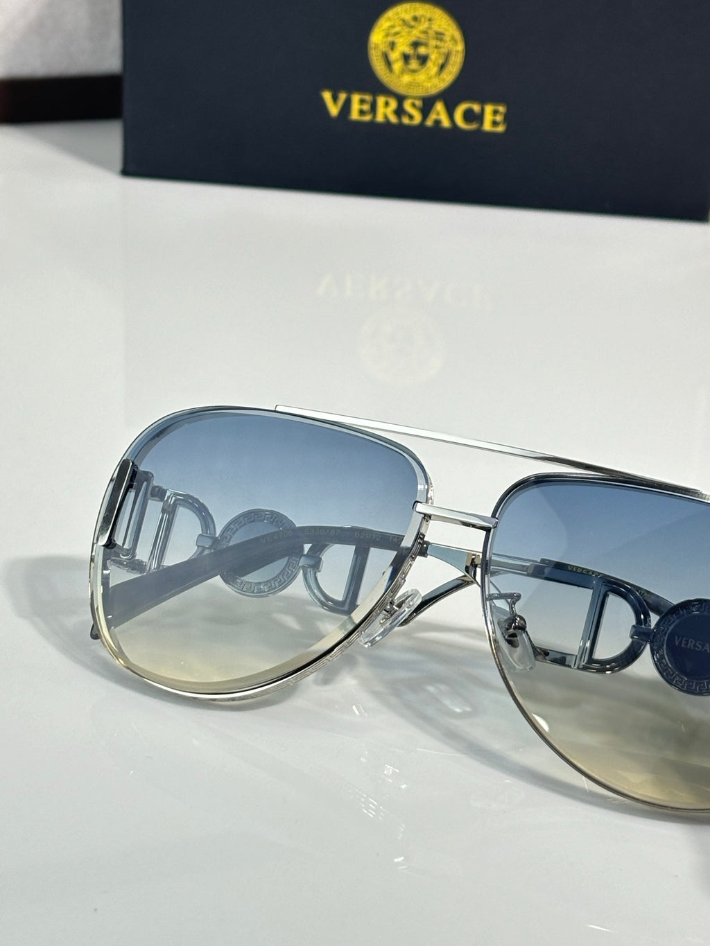 Versace sunglasses close-up with blue lenses and gold metal frame details