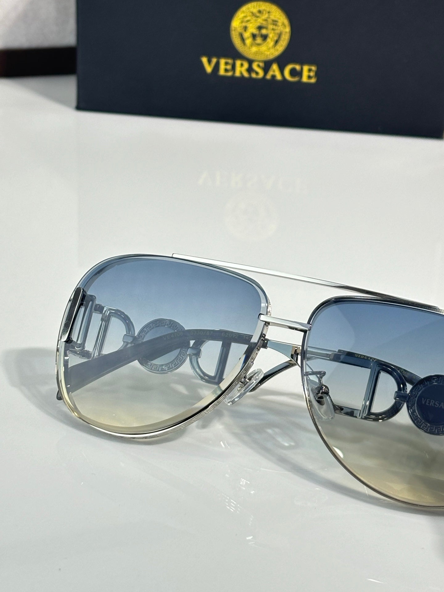 Versace sunglasses close-up with blue lenses and gold metal frame details