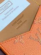 Louis Vuitton leather cardholder corner close-up with embossed text and orange monogram