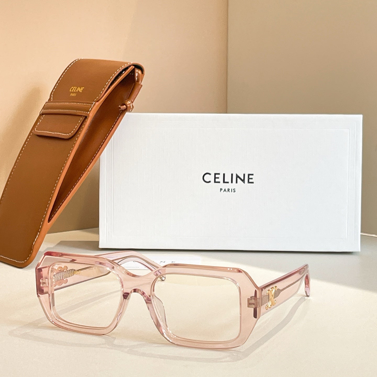 Light pink rectangular glasses with clear lenses and gold logo detail on temple