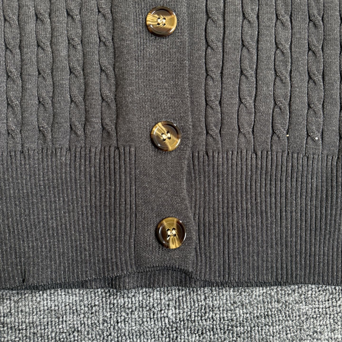 Dark gray cardigan front with gold-tone button closure