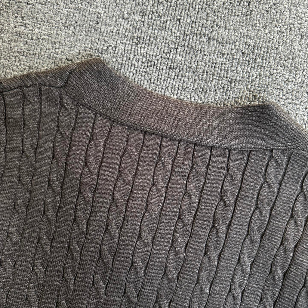 Dark gray cable-knit cardigan neckline with ribbed collar and vertical cable rows