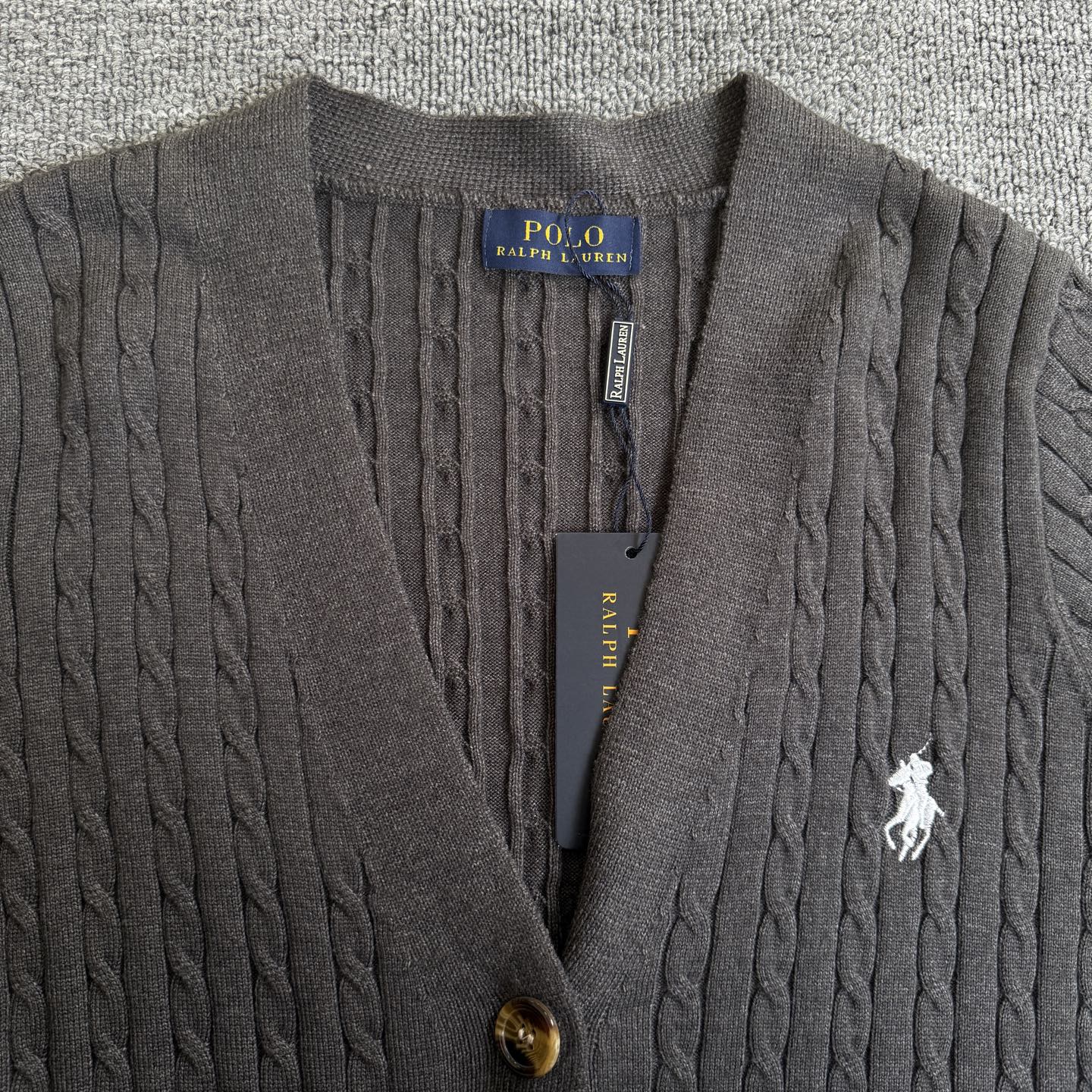 Dark gray cable-knit cardigan close-up with Polo Ralph Lauren patch, buttons, horse logo